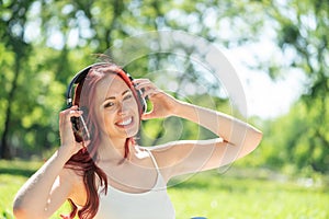 Young woman happens to have music in a summer park