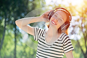 Young woman happens to have music in a summer park