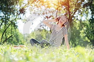 Young woman happens to have music in a summer park