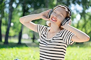 Young woman happens to have music in a summer park