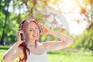 Young woman happens to have music in a summer park