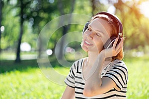 Young woman happens to have music in a summer park