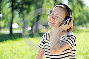 Young woman happens to have music in a summer park