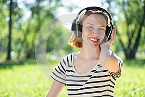 Young woman happens to have music in a summer park