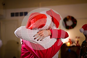 A young woman happily hugs her mother at a family Christmas celebration.