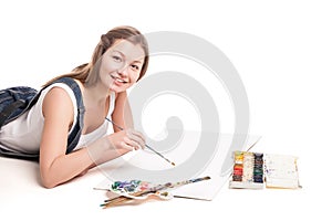 Young woman happily lies on the floor drawing in