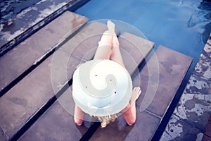 Young woman happy in big hat relaxing on the swimming pool, travel near the sea and beach. Concept summer