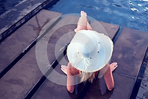 Young woman happy in big hat relaxing on the swimming pool, travel near the sea and beach. Concept summer