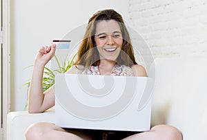 Young woman happy at home couch with computer and credit card internet on line shopping