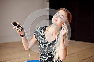 Young woman happy singing her favorite song while listening music sitting on the floor.