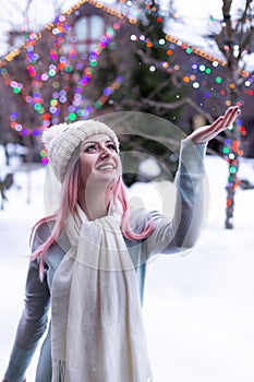 Young woman happy in a toque catching snowflakes with a snowy background.