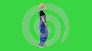 Young woman in hard hat and medical mask walking on a Green Screen, Chroma Key.