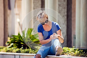 Young woman has knee pain during outdoor walking. Healthcare, medicine, people concept