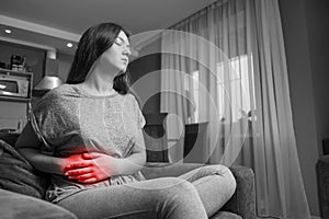 Young woman has pain in right hypochondrium, young woman has a stomachache, black and white photo, red accent, gallbladder disease