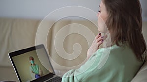 Young woman has a video call from her home with a doctor therapist who explains the symptoms of covid-19. Telemedicine