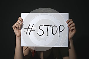 Young woman with hashtag STOP on background. Domestic violence concept