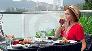 Young woman in a hat and dress on dinner with a glass of whiskey