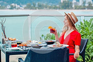 Young woman in a hat and dress on dinner with a glass of whiskey