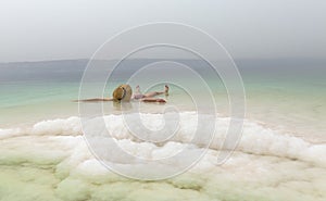 Young woman with hat floating in the waters of the Dead Sea