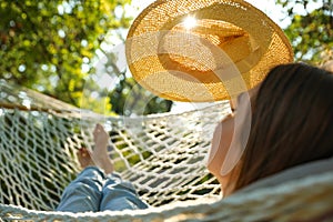 Young woman with hat resting in comfortable hammock at garden, closeup