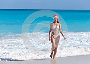 The young woman in a hat of Santa Claus on a beach
