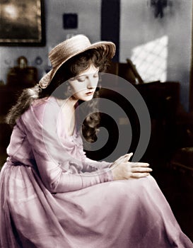 Young woman in a hat sitting and looking sad photo