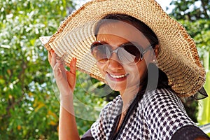 Young woman in a hat and sunglasses standing on a balcony