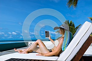 Young woman in hat with tablet pc at the beach