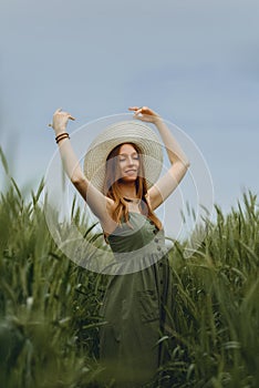 Young woman in a hat walking in a wheat field, enjoys life and summer. Wheat field.Healthy lifestyle Concept