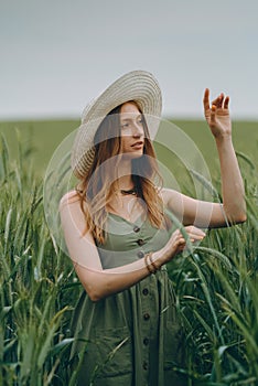 Young woman in a hat walking in a wheat field, enjoys life and summer. Wheat field.Healthy lifestyle Concept