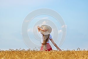 Young woman in hat on wheat field and sky background. Freedom relax a naturalness