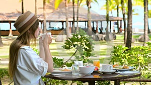 Young woman have breakfast in luxury sea view hotel at outdoor resort restaurant