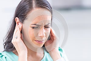 Young woman have headache migraine stress or tinnitus - noise whistling in her ears