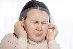 Young woman have a headache migraine stress or tinnitus - noise whistling in her ears.