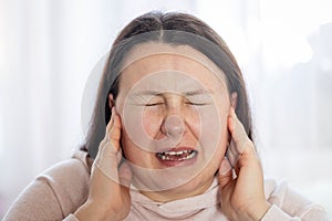 Young woman have headache migraine stress or tinnitus - noise whistling in her ears.