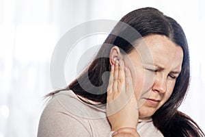 Young woman have a headache migraine stress or tinnitus - noise whistling in her ears