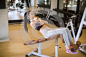 Young woman have a training at sit up bench in the gym