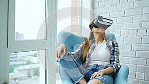 Young woman have VR experience using virtual reality headset sitting in chair on balcony