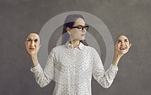 Young woman having bipolar disorder holding two face masks with opposite emotions