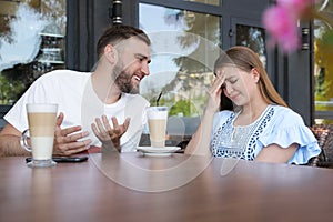 Young woman having boring date with talkative guy in outdoor cafe