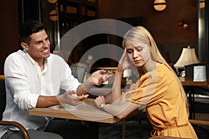 Young woman having boring date with talkative man in cafe