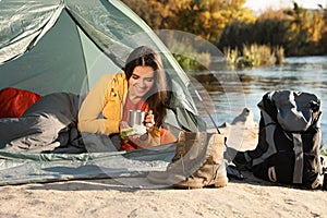 Young woman having breakfast in sleeping bag