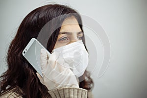 Young woman having a call on a cellphone working from home during quarantine due to coronavirus pandemia. Beautiful girl stays