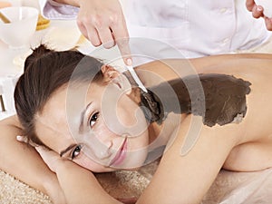 Young woman having clay body mask.