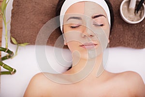 Young woman having clay skin mask treatment on her face