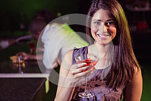 Young woman having cocktail at bar counter