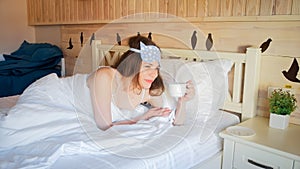 Portrait of young woman having coffee in bed at morning