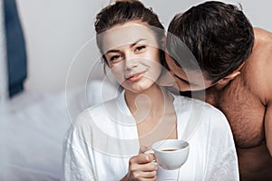 Young woman having coffee with boyfriend in bed