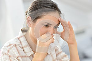 Young woman having a cold blowing her nose