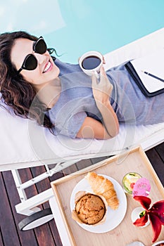 Young woman having cup of tea near poolside